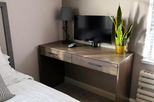 Meuble en bois avec écran, lampe et plante verte